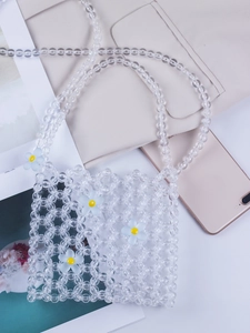 Detail of transparent acrylic beaded bag with blue and white daisy floral charms