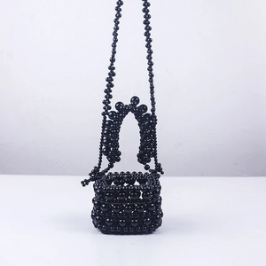 Detail of handcrafted black acrylic beaded mini bucket bag with glossy woven texture