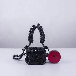 Detail of handcrafted black acrylic beaded mini bucket bag with glossy woven texture