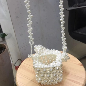 Detail of handcrafted white acrylic pearl bucket bag with beaded shoulder strap