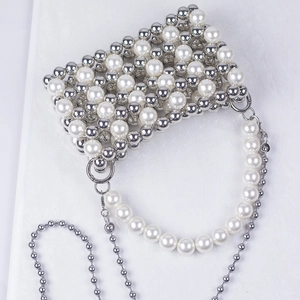 Macro shot of hand-woven pearl and silver metal bead texture on elegant evening bag