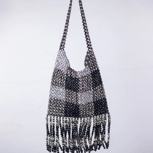 Detail of handmade beaded handbag featuring black and silver checkerboard and tassel trim