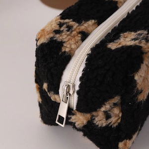 Close-up of leopard print plush cosmetic bag with white zipper and metal puller detail