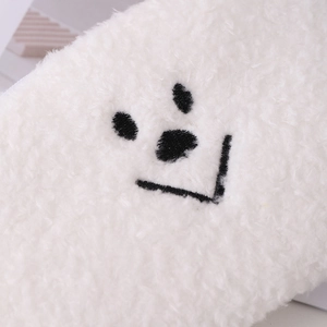 Gros plan sur la trousse en peluche blanche montrant la texture douce et le motif de sourire