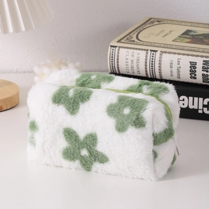 Detailed macro view of plush white stationery pouch with green floral embroidery and zipper