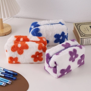 Close-up of plush floral pencil cases in white, orange, and purple soft faux fur