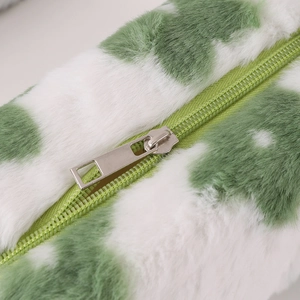 Close-up of green and white cow print plush pencil case with smooth zipper detail