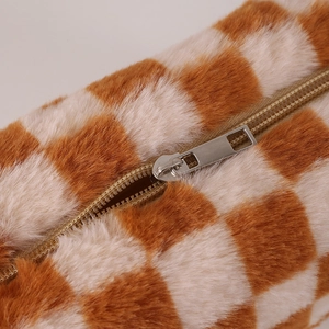 Detail of plush orange and beige checkered pencil case with soft texture and metal zipper