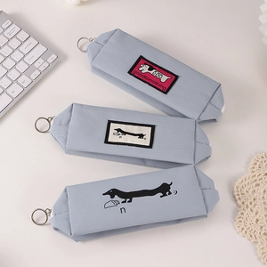 Light blue dachshund canvas pencil case set with metal zippers on a minimalist desk