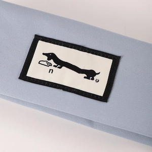 Detailed macro view of a light blue fabric pencil case with a dachshund patch label
