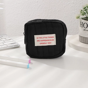 Close-up of a black quilted mini cosmetics bag with a motivational quote label