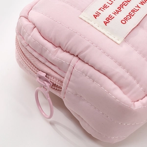Detail of pink quilted cosmetic bag showing soft texture and white woven label