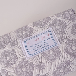 Detailed close-up of quilted floral fabric and logo patch on large stationery bag