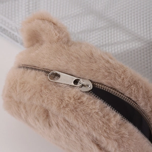 Detail of soft brown plush bear coin purse showing the metal zipper and fuzzy texture