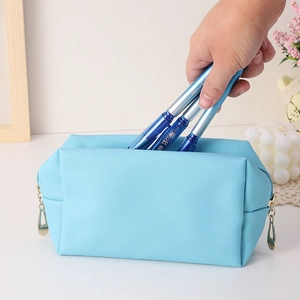 Detailed close-up of light blue textured PU makeup bag with golden double zippers