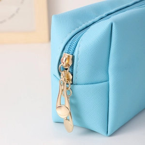 Detail of light blue PU makeup bag showing cross-grain texture and golden metal zippers