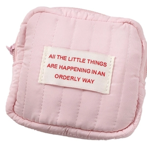 Pink quilted mini cosmetic bag with motivational text label and zipper closure