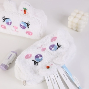 Gros plan sur une trousse lapin en peluche blanche avec oreilles carotte et broderie