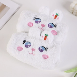 Détail de trousses lapin en peluche blanche avec broderies et décor de carotte