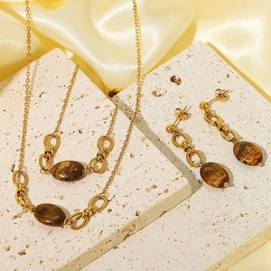 Parure bijoux vintage en acier doré avec pierres œil de tigre sur support en pierre