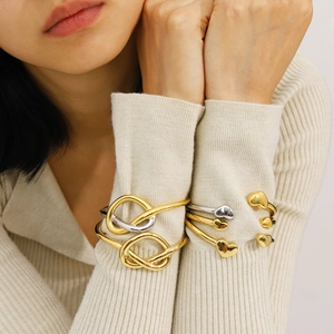 Bracelet jonc à nœud en acier poli et bracelets à breloques cœur sur un poignet