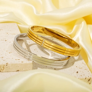 Gold and silver stainless steel bangles set with three small diamonds on rock stand