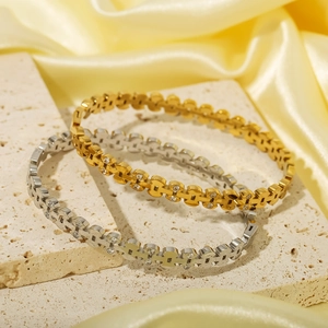 Gold and silver stainless steel bangles with diamonds on stone and silk background