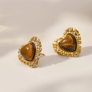 Detail of heart-shaped gold studs with brown tiger eye stone and vintage texture