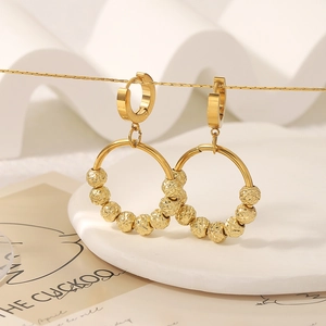 Gold plated stainless steel hoop earrings with textured beads on a display stand