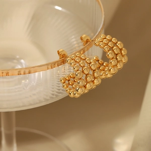 Boucles d'oreilles créoles C multicouches perlées en plaqué or 18k sur un verre