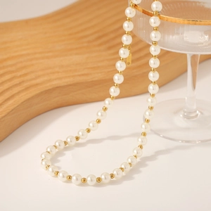 Collier de perles baroques avec perles dorées et acier doré 18 carats sur un verre