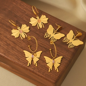 Three pairs of vintage gold butterfly earrings with zircon and natural stones on wood