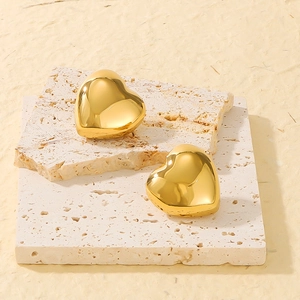 Detail of 3D gold heart earrings on stone board with polished stainless steel finish