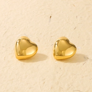 Detail view of 3D heart-shaped gold earrings with highly polished metallic surface
