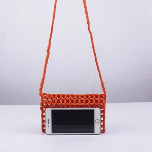 Close-up of orange acrylic beaded bag showing storage capacity with a smartphone