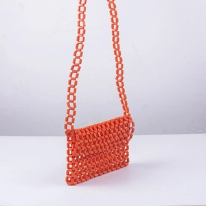 Detail of bright orange handmade beaded crossbody bag with hollow checkered pattern weave