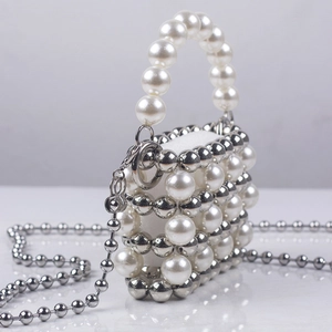 Close-up of handmade mini pearl evening bag with silver metal beads and chain strap