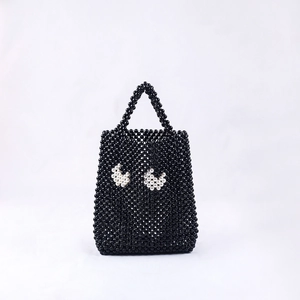 Détail d'un sac à main noir perlé à la main avec des motifs de cœurs en perles blanches