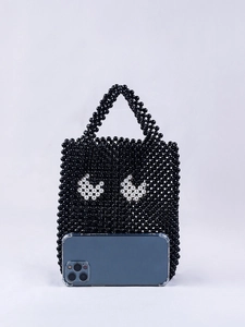 Vue détaillée du mini sac perlé à motif yeux montrant la taille par rapport au téléphone