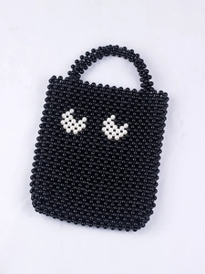Détail d'un sac à main fait main en perles avec des motifs de croissants blancs sur noir