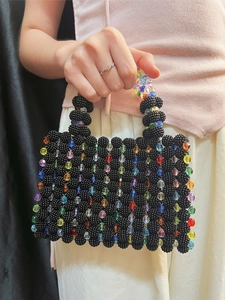 Detail of handmade beaded handbag featuring colorful rainbow beads on black woven surface