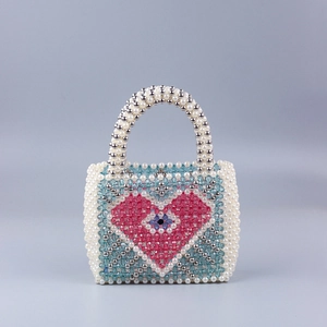 Detail of handmade beaded handbag with pink heart pattern and pearl handle for party wear