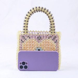 Beaded heart handbag next to a purple smartphone for size comparison showing handcraft