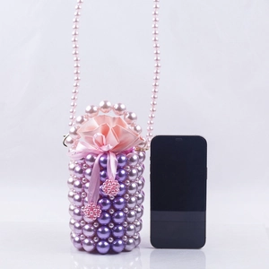 Detail view of handmade purple pearl bucket bag next to a phone for size comparison