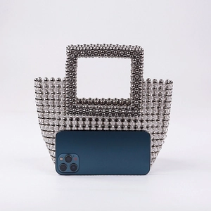 Handmade beaded evening clutch with acrylic handle and silver-grey beads next to a phone