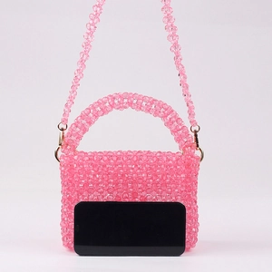 Sac à main rose fait main en perles avec fermoirs dorés et smartphone pour comparer la taille