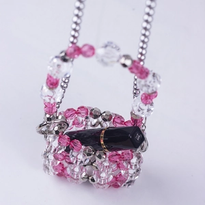 Macro view of a mini handmade beaded bag with crystals and a lipstick for scale