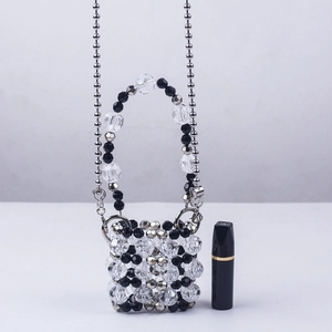 Macro shot of handmade mini acrylic beaded bag with metallic chain and lipstick for scale