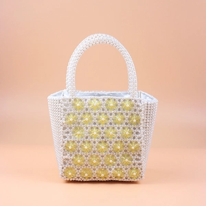 Macro detail of hand-beaded tote with cream pearls and bright yellow acrylic flowers