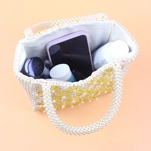Spacious interior of white pearl beaded bag showing phone and cosmetics inside